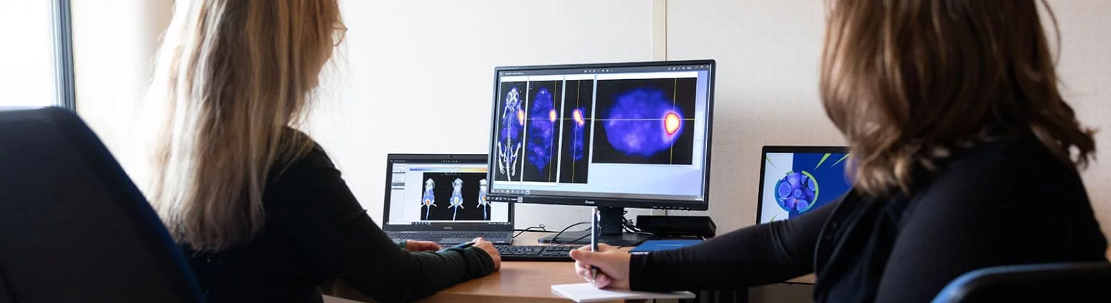 Two scientists reviewing imaging data for theranostic development at Oncodesign Services